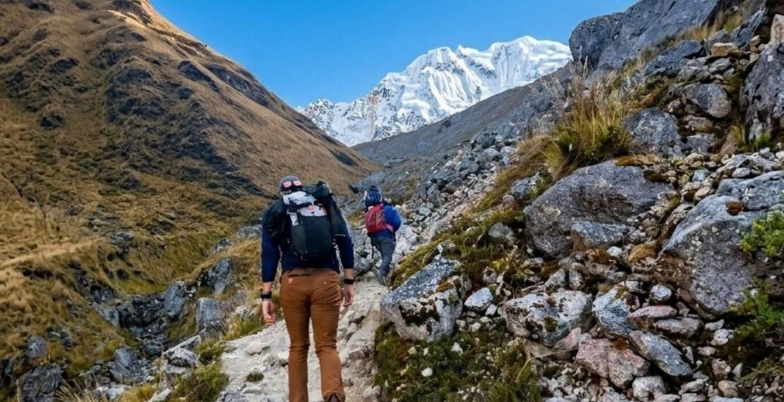Viajeros ascendiendo por el sendero rocoso hacia el nevado en la portada del Salkantay Trek de 5 días. Viajes en Cusco.