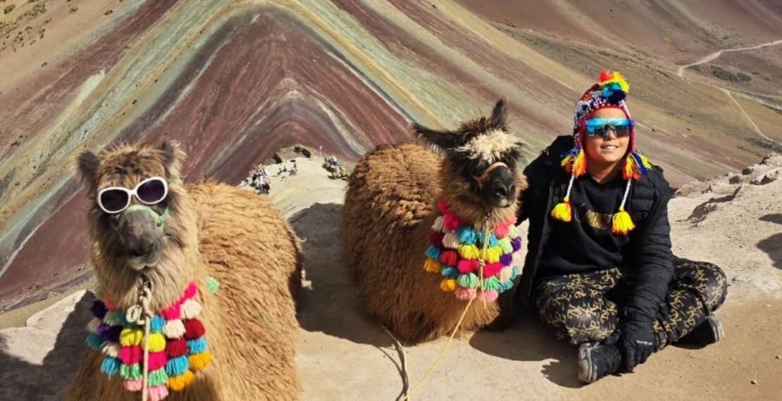 Viajero posando junto a dos llamas con lentes en la portada del tour a Cusco de 6 días. Viajes en Cusco.