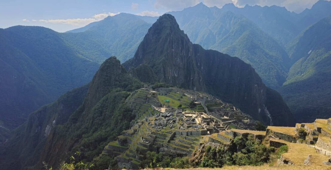 Vista clásica de la ciudadela de Machu Picchu con Huayna Picchu al fondo. Excursiones y viajes a Cusco.