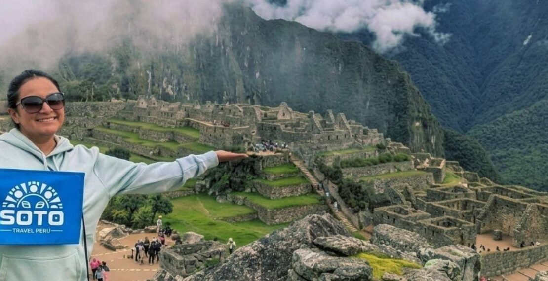 Viajera con la bandera de la agencia en Machu Picchu en la portada del tour Valle Sagrado VIP con Machu Picchu. Viajes en Cusco.