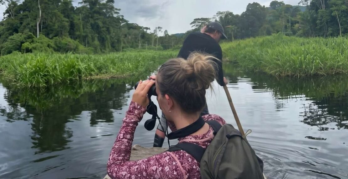 Viajera observando aves con binoculares en una laguna en la portada del tour Cusco y Manu de 10 días. Viajes en Cusco.