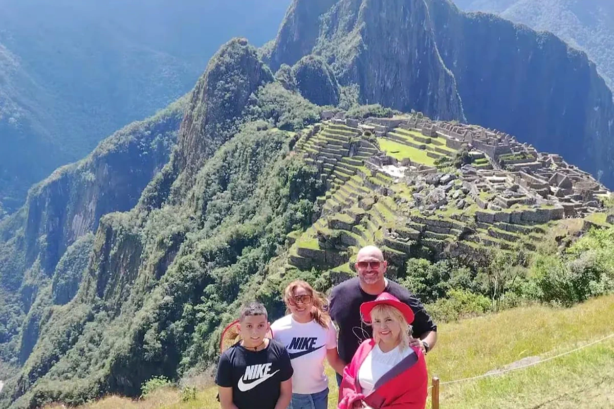 Familia de cuatro viajeros en el mirador panorámico de la ciudadela de Machu Picchu en Cusco, Perú