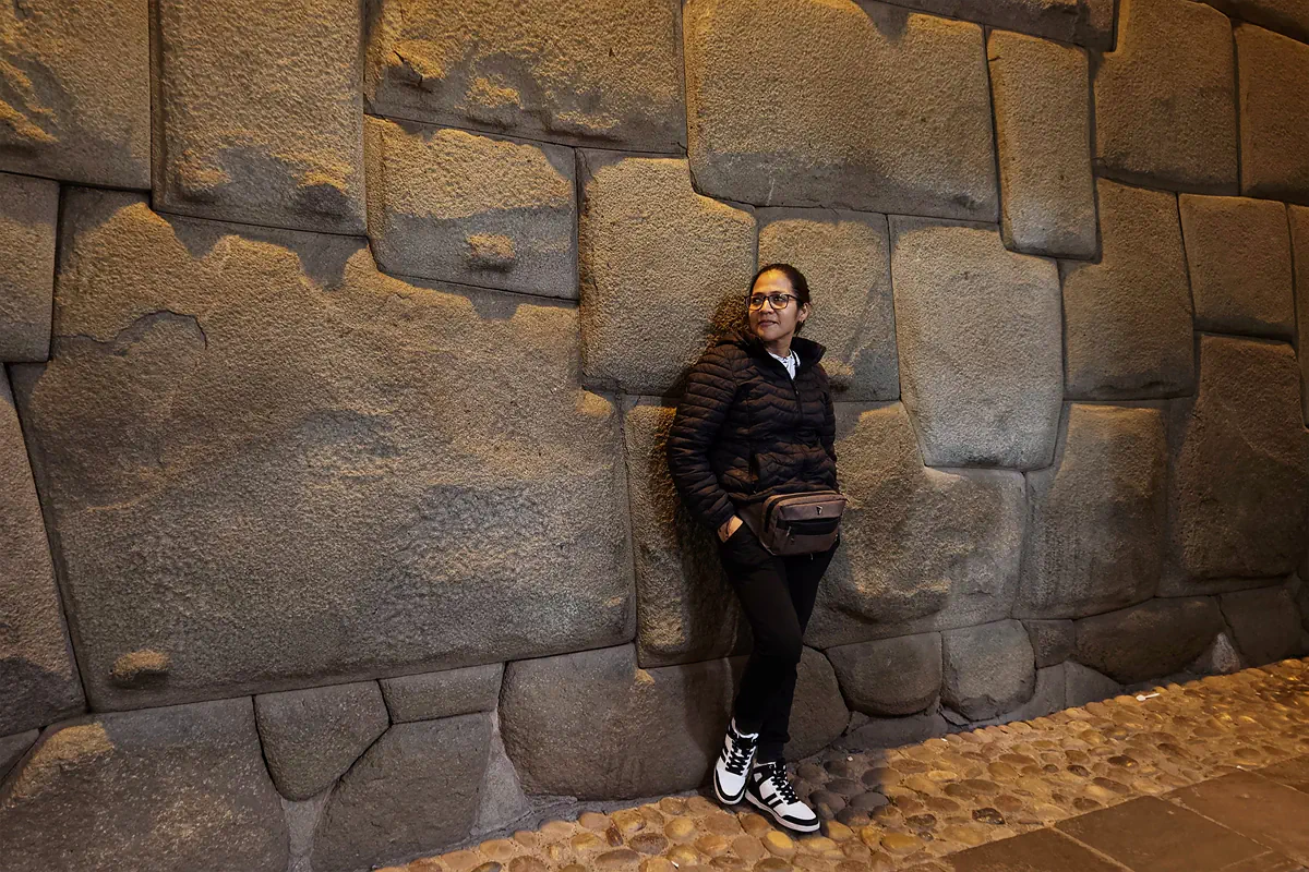 Viajera junto al muro inca de la calle Hatun Rumiyoc y la Piedra de los 12 Ángulos en Cusco, Perú
